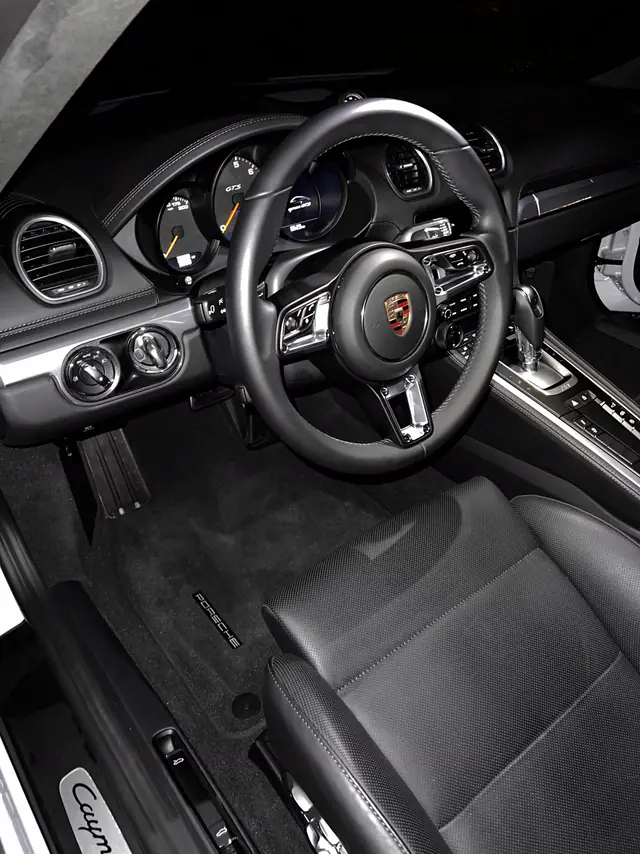 Porsche 718 Cayman GTS steering wheel and dash at night, freshly detailed.